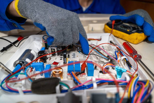 Technician repairs electronic circuit board in workshop during daylight hours